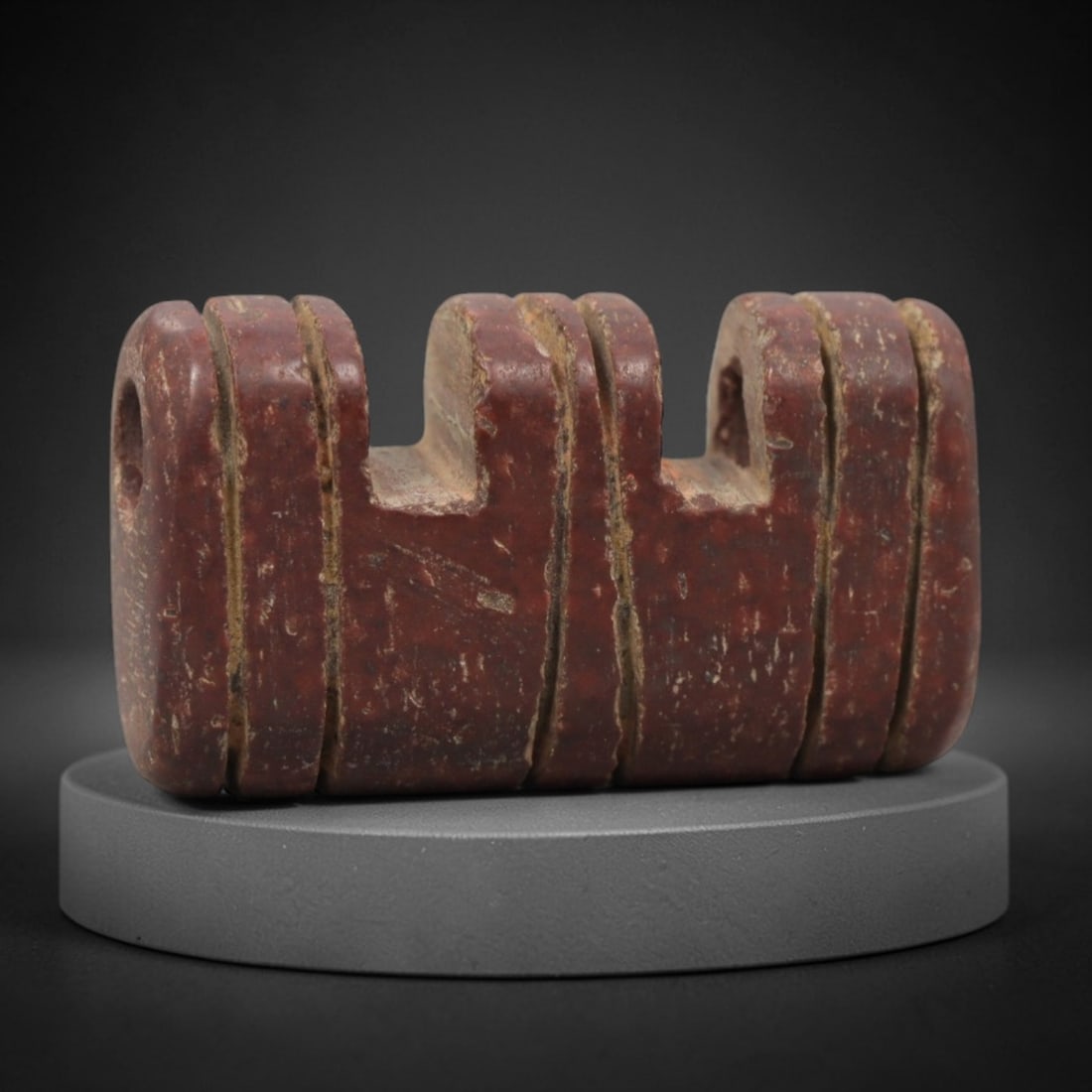 Ancient Near Eastern Red Stone Triple Amulet - Carved Bead, 57ZV: This amulet is carved from a rich, deep red stone with natural speckling, likely brecciated jasper or red steatite, featuring a symmetrical triple-form design. The piece is composed of three adjacent