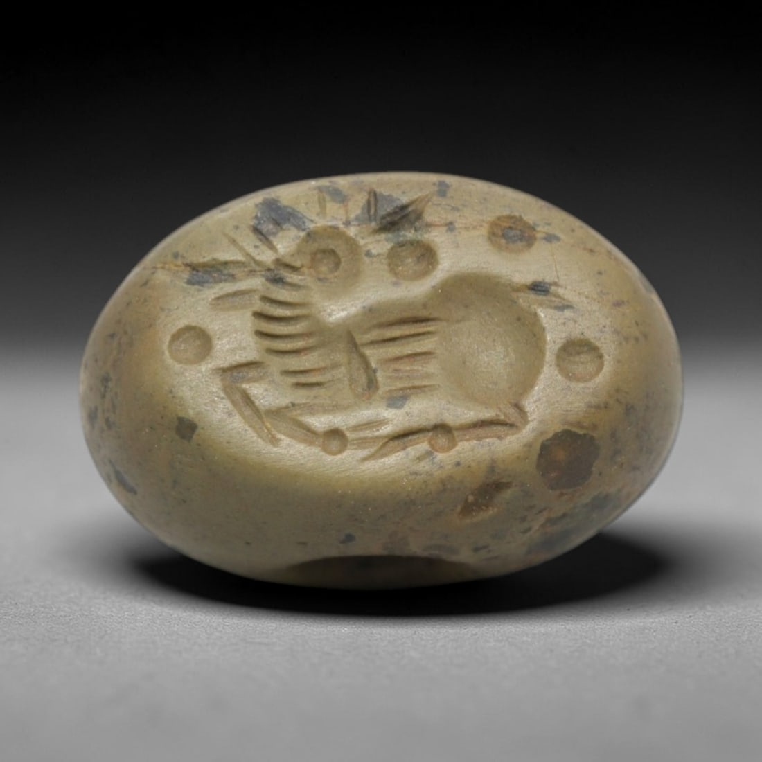 Ancient Stone Hemispherical Stamp Seal - Near Eastern Animal Figure, 68ZS: Crafted from dense, light greenish stone, this hemispherical stamp seal bears incised carving of a stylized animal figure, likely a hare or rodent, with linear body detailing, ear motifs, and surround