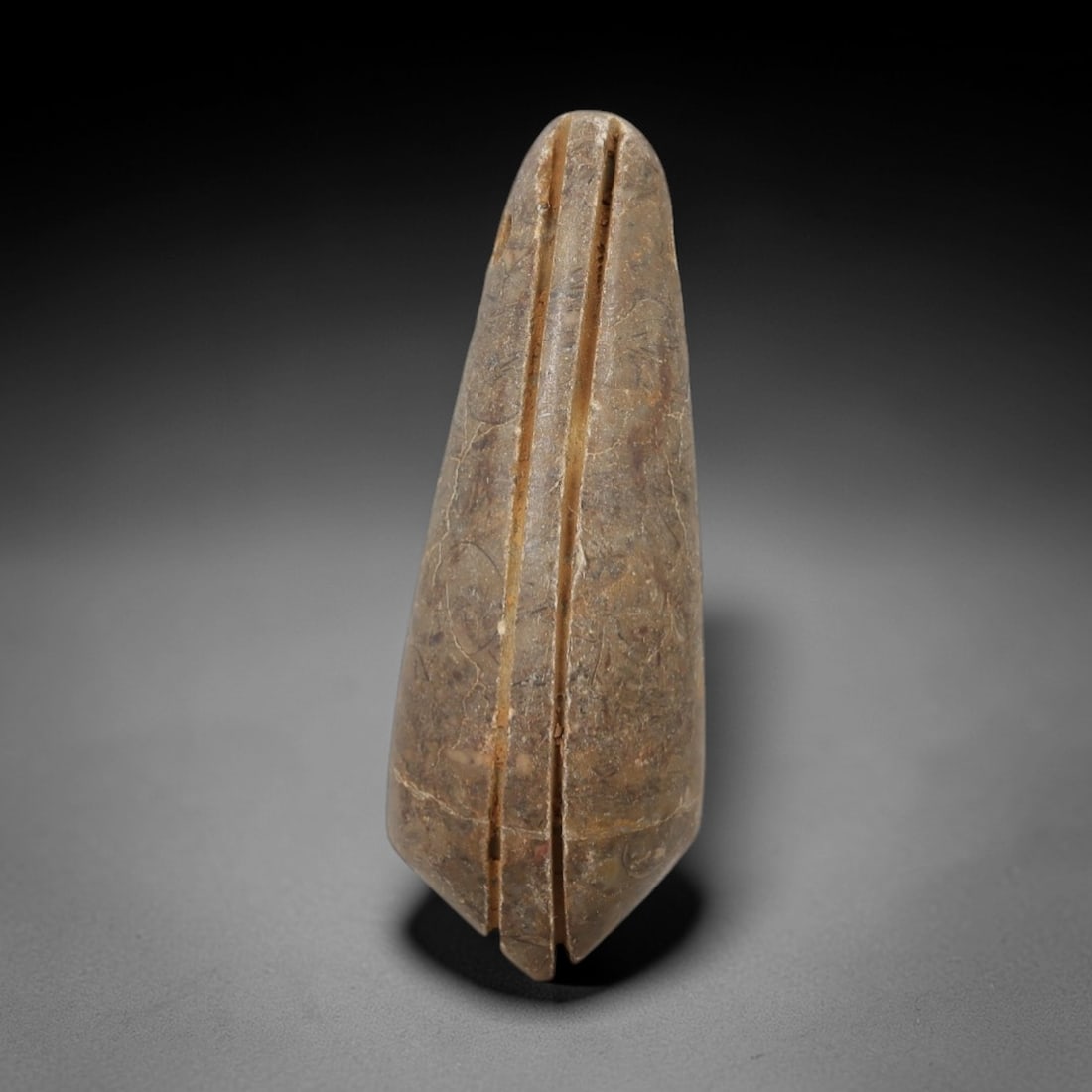 Ancient Egyptian Stone Amulet - Geometric Carved Pendant, 16AE: Carved from light-toned stone, this ancient Egyptian amulet features a tapering, elongated form with incised geometric detailing, a motif typical of Egyptian protective amulets. Craftsmanship is simpl