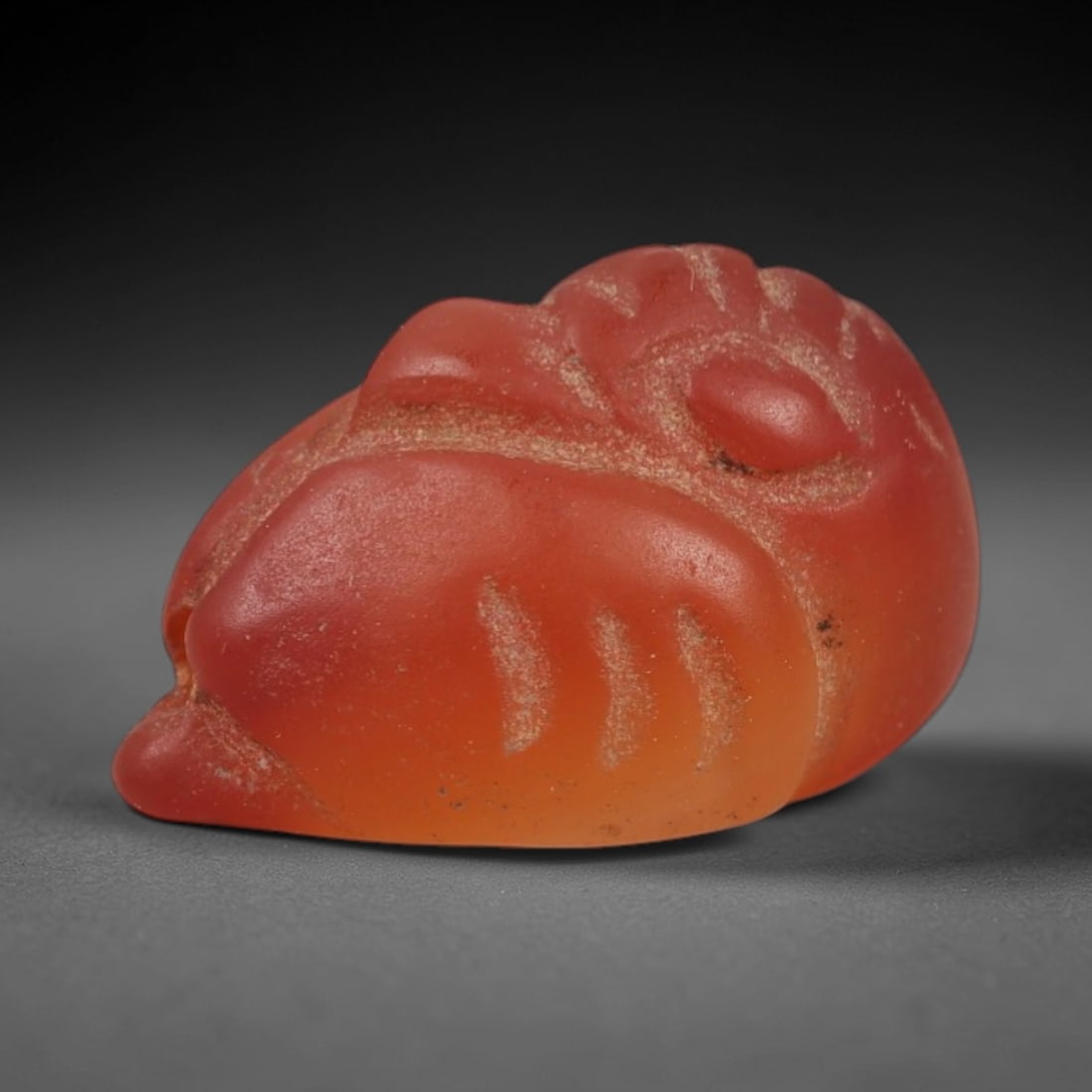 Ancient Carnelian Duck Amulet - Egyptian Figurine, 46AJ: Carved from warm, translucent orange-red carnelian with natural color gradients, this amulet is formed as a stylized duck with incised linear detailing to define the head, beak, wing contours, and bod