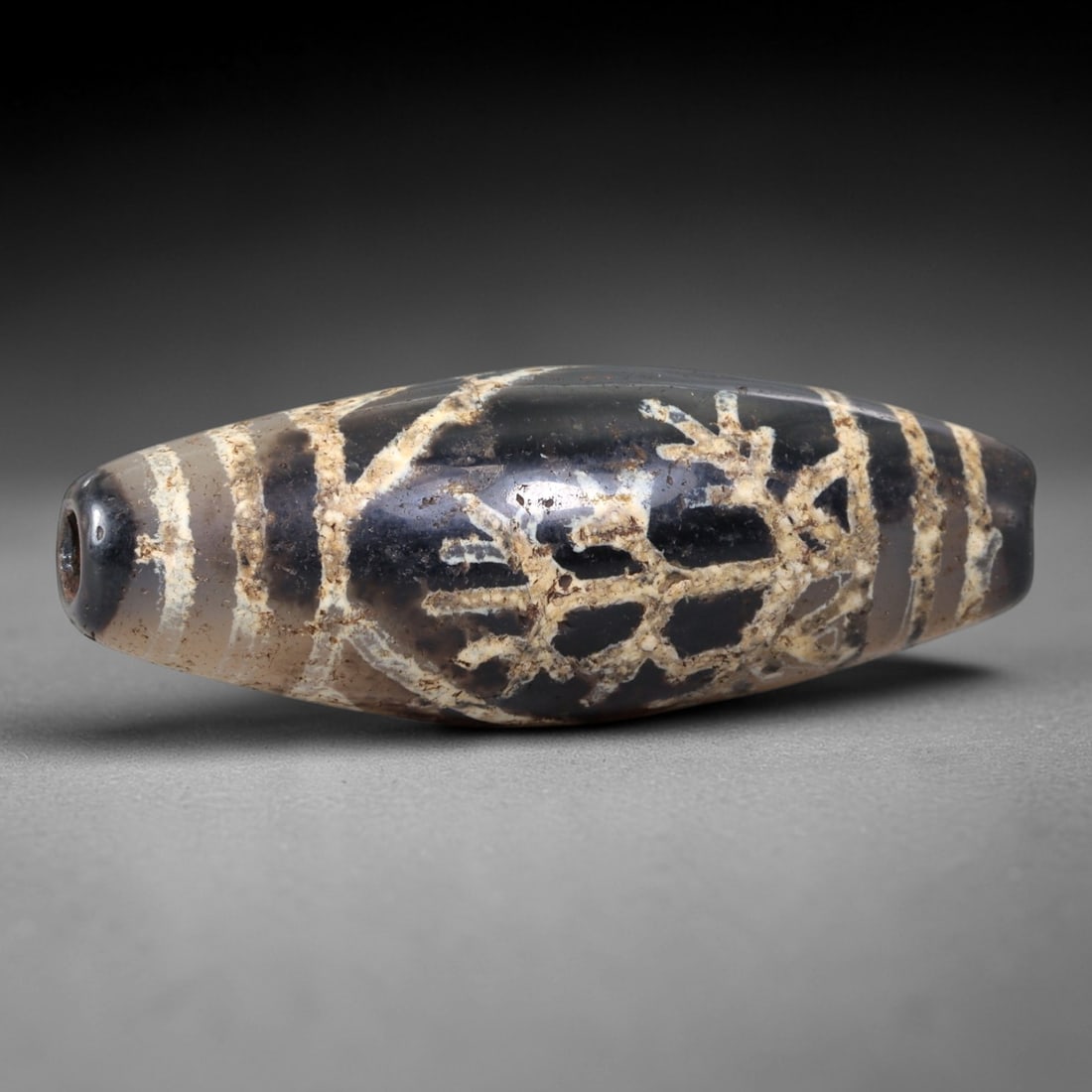 Ancient Agate Dzi Bead - Himalayan Tree of Life Amulet, 4AS: This ancient elongated bead is crafted from polished banded agate, featuring a dark smoky-brown base with intricate white etched "Tree of Life" and linear motif patterns across its surface. The bead r