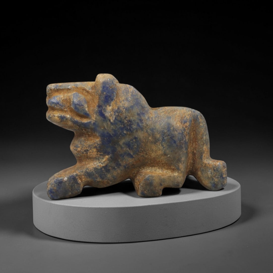 Ancient Lapis Lazuli Feline - Near Eastern Amulet Figurine, 97XV: Carved from lapis lazuli, this amulet depicts a striding feline in a dynamic predatory stance with angular, stylized features. The head is prominent with incised eye and snout detailing, small upright