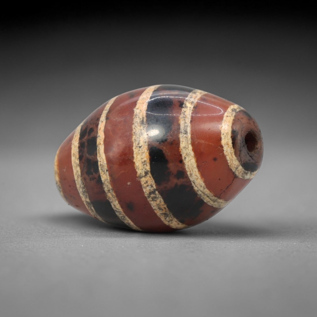Ancient Carnelian Etched Dzi Bead - Himalayan Amulet, 71XV: Crafted from rich carnelian, this bead features bold etched white parallel band patterns alternating with dark inlaid sections, executed in the traditional Himalayan Dzi bead craftsmanship. The form i