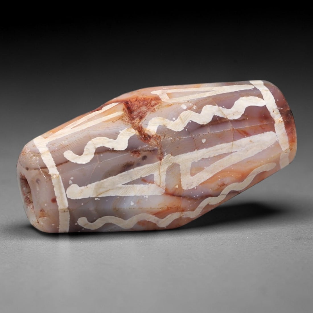Ancient Agate Etched Bead - Himalayan Amulet Pendant, 6AS: This ancient tapered bead is crafted from polished banded agate, featuring a warm pinkish-brown base with contrasting white etched wavy and linear geometric motifs across its surface. The bead retains