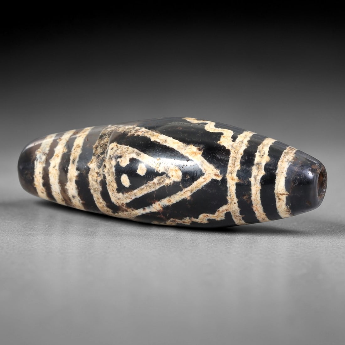Ancient Agate Etched Dzi Bead - Himalayan Amulet, 10AS: Crafted from dark translucent agate, this bead displays elaborate etched white geometric patterns, including a central triangular motif flanked by parallel linear bands, executed in the traditional Hi