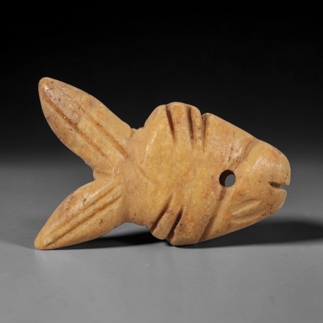 Ancient Steatite Fish Amulet - Egyptian Ritual Pendant, 63AR: Carved from steatite, this fish amulet follows the stylized form characteristic of ancient Egyptian protective magic. The piece features incised linear details defining the fins, tail, and facial stru