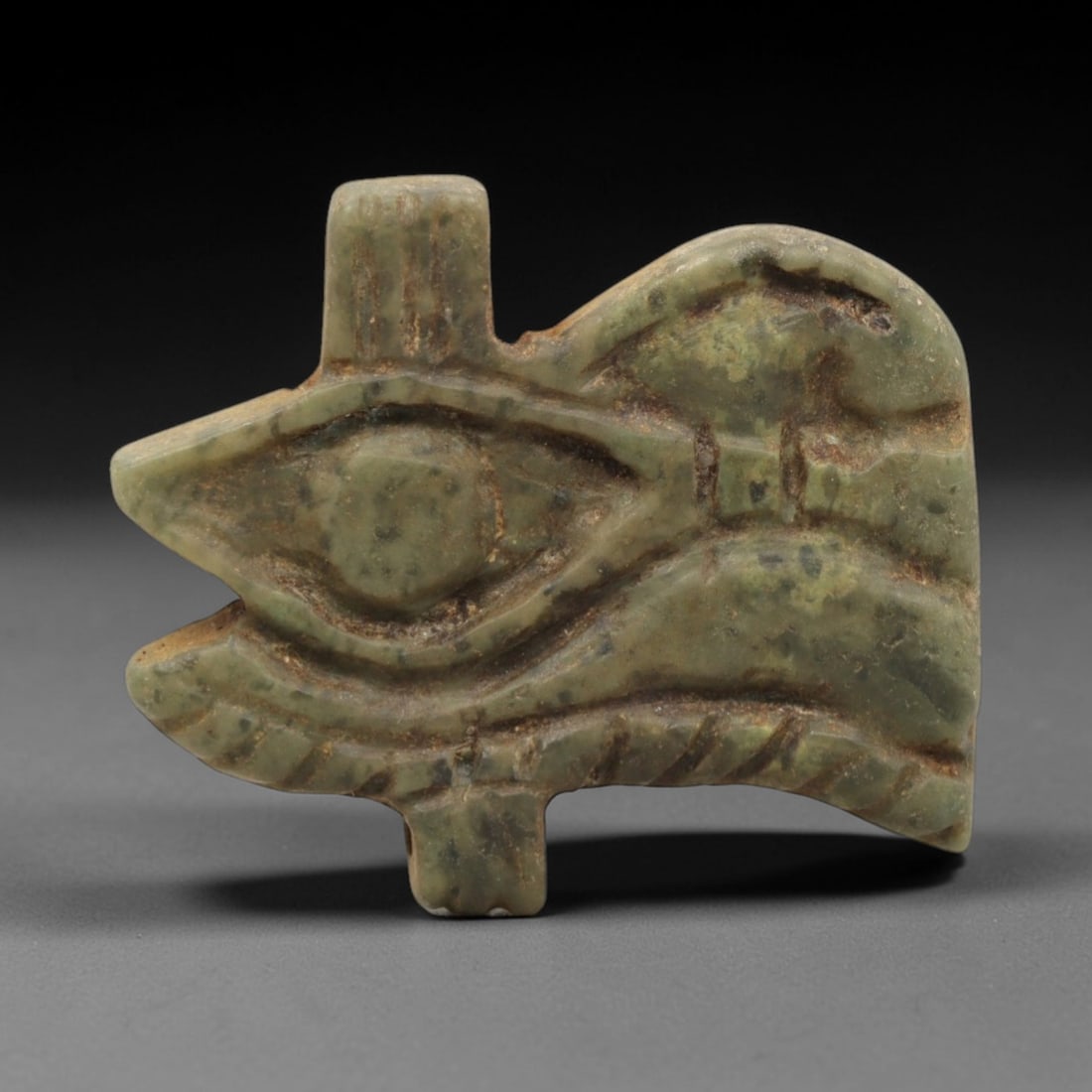 Ancient Serpentine Wedjet Eye Amulet - Egyptian Figurine, 88ZP: This artifact is a carved serpentine Wedjet Eye amulet, executed in the iconic protective tradition of ancient Egypt. The amulet depicts the Wedjet (or Eye of Horus) with distinct incised details: a c