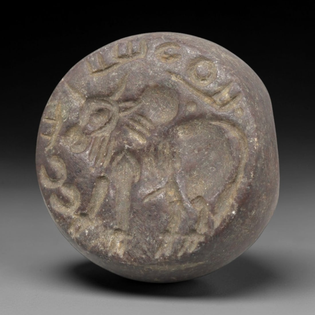 Ancient Stone Hemispherical Stamp Seal - Near Eastern Bull & Script, 45ZP: Crafted from a dense, reddish-brown stone, this hemispherical stamp seal bears a deeply incised depiction of a stylized bull, rendered in linear relief with distinct horned head, robust torso, and stu