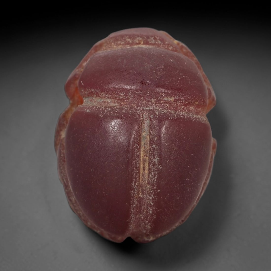 Ancient Carnelian Scarab Amulet - Egyptian Figurine, 31XS: Carved from rich, deep rose-red carnelian with subtle amber undertones and natural mineral patination, this amulet is formed as a stylized scarab beetle with incised linear detailing to define the cen