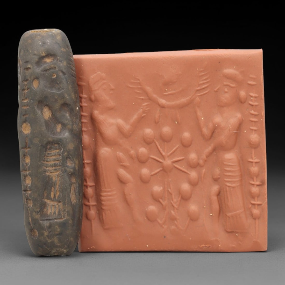 Ancient Steatite Cylinder Seal - Mesopotamian Sacred Tree Scene, 80ZR: Carved from dense steatite, this ancient Mesopotamian cylinder seal features a detailed linear relief composition of two human figures flanking a central sacred tree, executed in the characteristic gl