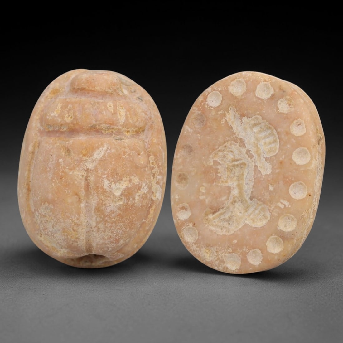 An Ancient Near Eastern Stone Scarab Stamp Seal, 1st Millennium BCE, 89AC: Carved from pale pinkish stone with natural surface patination and subtle tonal variation, the object is formed as an oval scarab seal. The dorsal side is modeled in low relief with a segmented carapa