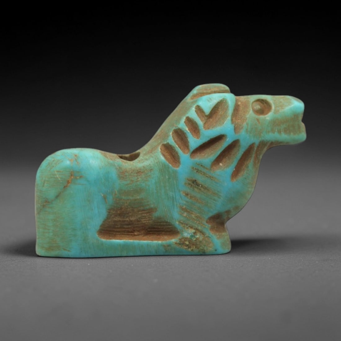 Ancient Turquoise Horse Amulet - Egyptian Animal Figurine, 24ZS: This artifact is a carved turquoise horse amulet, executed in the stylized zoomorphic tradition of ancient Egypt. The amulet depicts a recumbent horse with simplified anatomical features, including a