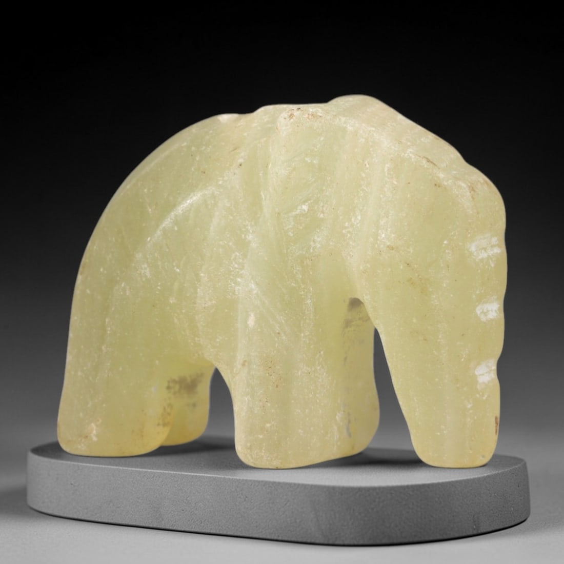 Ancient Serpentine Elephant - Egyptian Animal Figurine, 82AR: This artifact is carved from pale, yellowish-green serpentine, exhibiting a smooth, matte finish with subtle natural veining and minor surface wear consistent with age. The form is a stylized elephant