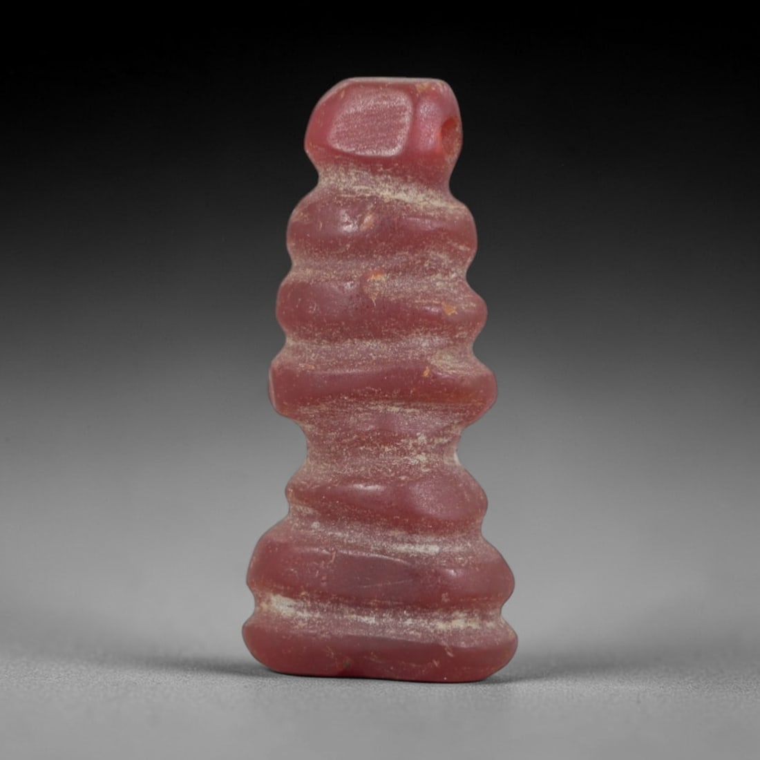 Ancient Djed Pillar Amulet - Egyptian Ritual Pendant, 91AP: This artifact is carved from variegated red stone with a weathered, earthy patina and subtle mineral inclusions, exhibiting the iconic tiered form of the Egyptian Djed pillar, consistent with ancient