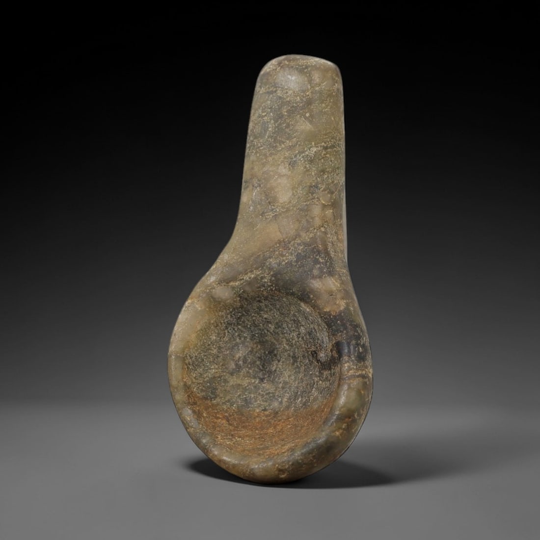 Ancient Stone Spoon Amulet - Near Eastern Ritual Figurine, 27AG: This amulet is carved from a single piece of mottled grey-green stone, exhibiting a fine-grained texture with subtle ochre patina and natural mineral veining across its surface. The form is a diminuti