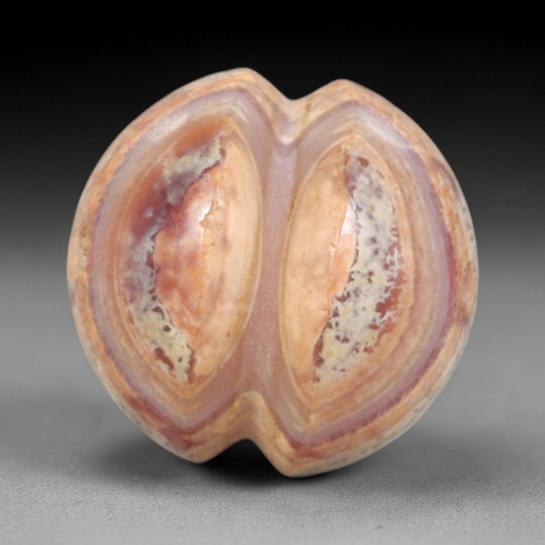 Antique Agate Double Eye Bead - Central Asian Gemstone Pendant, 7AR: Carved from banded agate with earthy pink, orange, and creamy white concentric banding, this bead features a symmetrical double-eye motif with a subtle heart-shaped indentation at the top and bottom.