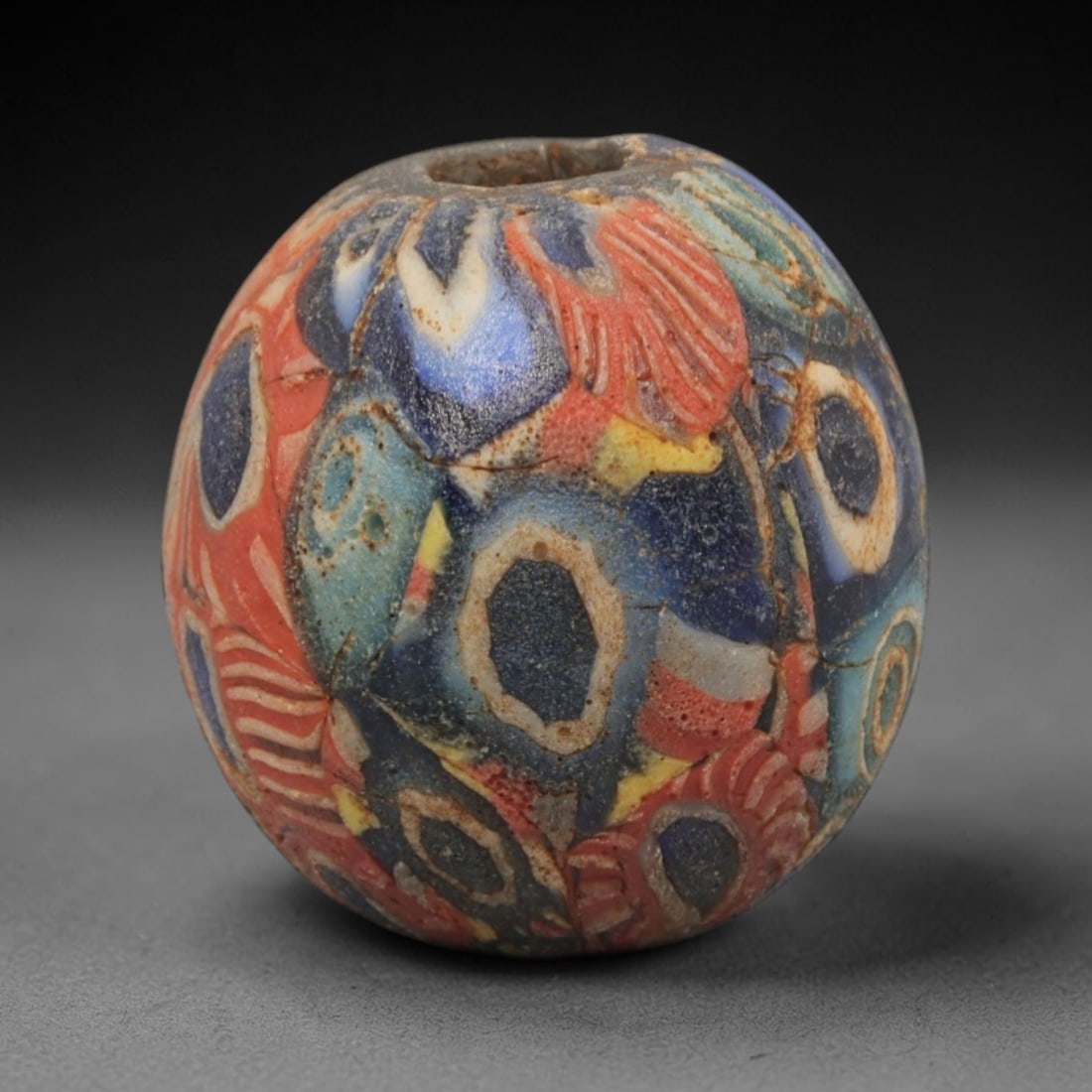Ancient Islamic Glass Bead - Mosaic Eye Trade Bead, 84ZN: Crafted from ancient glass, this Islamic period bead features a mosaic eye pattern with layered red, blue, yellow, and white glass trails applied to a translucent base, characteristic of decorative gl
