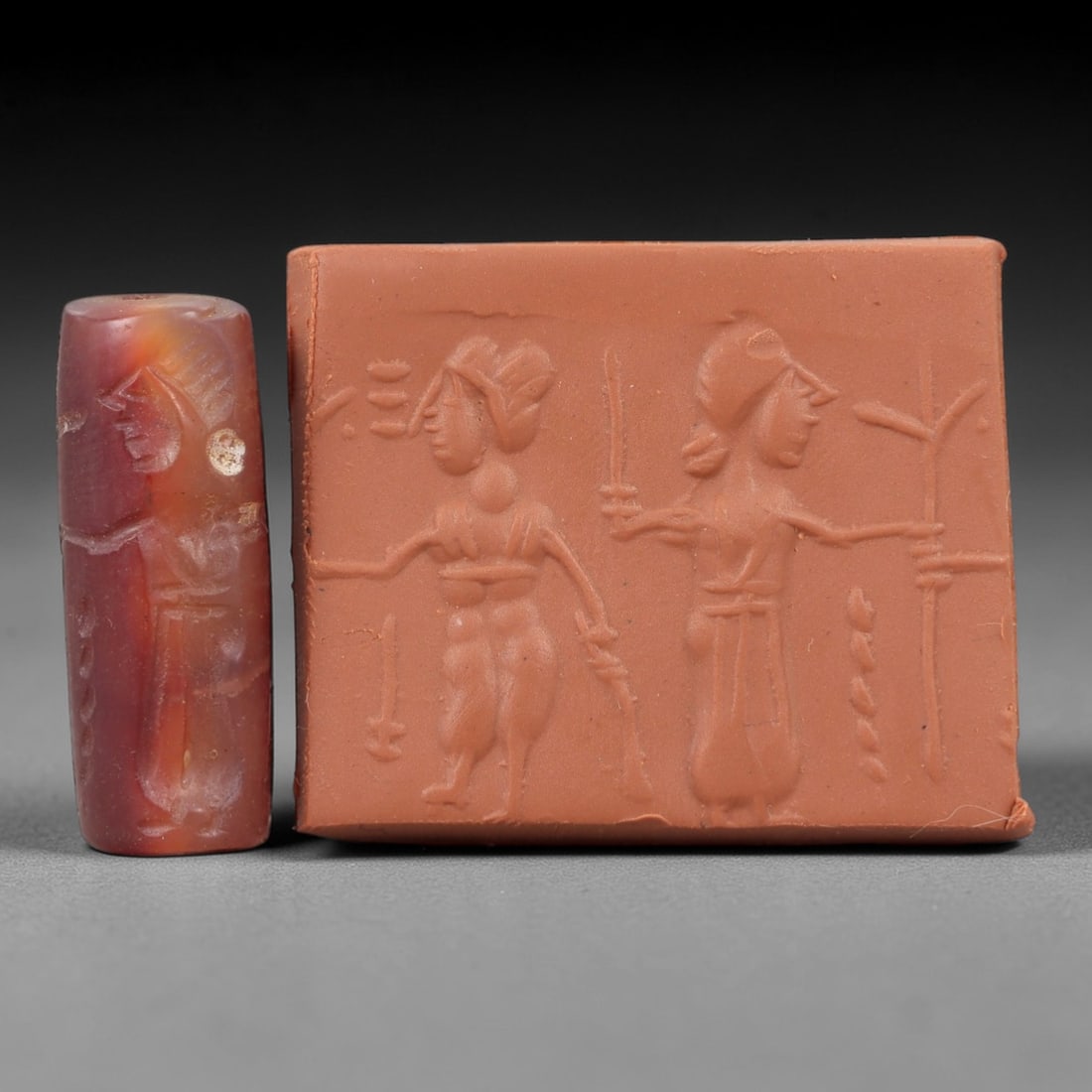 Ancient Carnelian Cylinder Seal - Mesopotamian Figural Procession Scene, 55AN: Carved from richly hued carnelian, this ancient Mesopotamian cylinder seal features a refined linear relief composition of two human figures in procession, one bearing weapons and the other extending