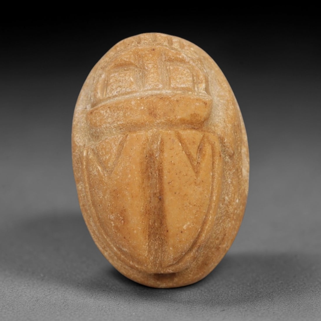 Ancient Stone Scarab Amulet - Near Eastern Relic, 2AE: Carved from warm tan sandstone, this amulet depicts a stylized scarab beeton, a motif revered for its associations with protection and regeneration in ancient Near Eastern iconography. The form is ren