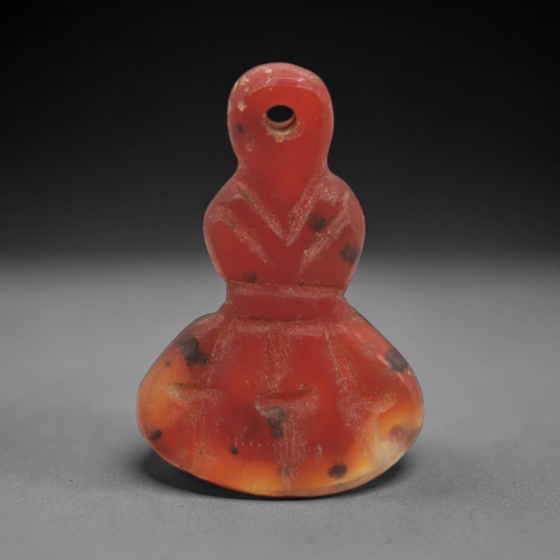 Ancient Agate Amulet - Near Eastern Figurine Pendant, 63XS: This amulet is carved from polished orange-red agate with natural dark inclusions, exhibiting the characteristic banding and translucency of ancient Near Eastern glyptic craft. The form is an anthropo