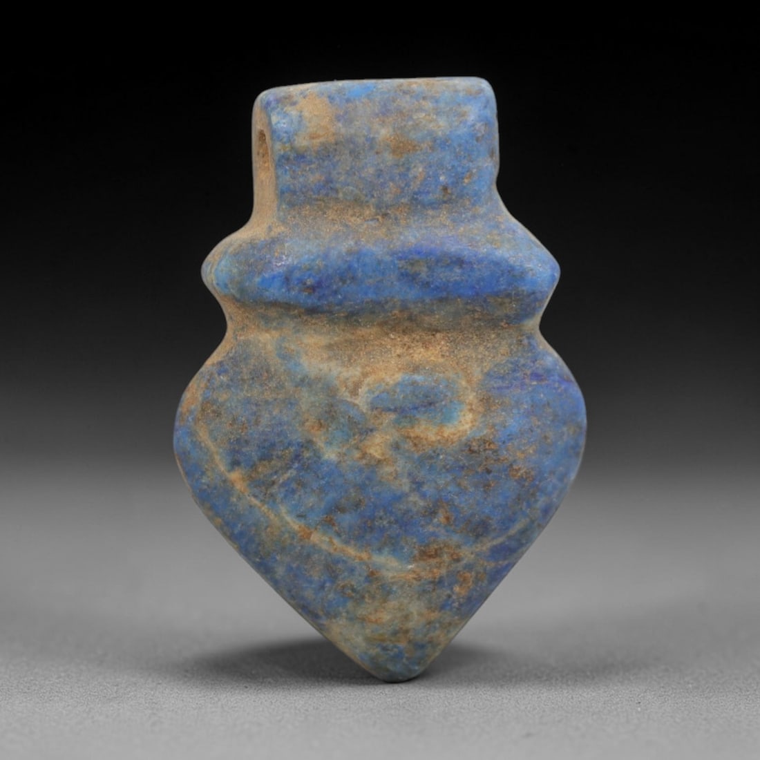 Ancient Lapis Lazuli Heart Amulet - Egyptian Ritual Pendant, 25ZT: Carved from lapis lazuli, this amulet is formed in a classic, robust heart shape, with a rectangular upper lug pierced for suspension, its body defined by a subtle raised collar at the shoulder and ta