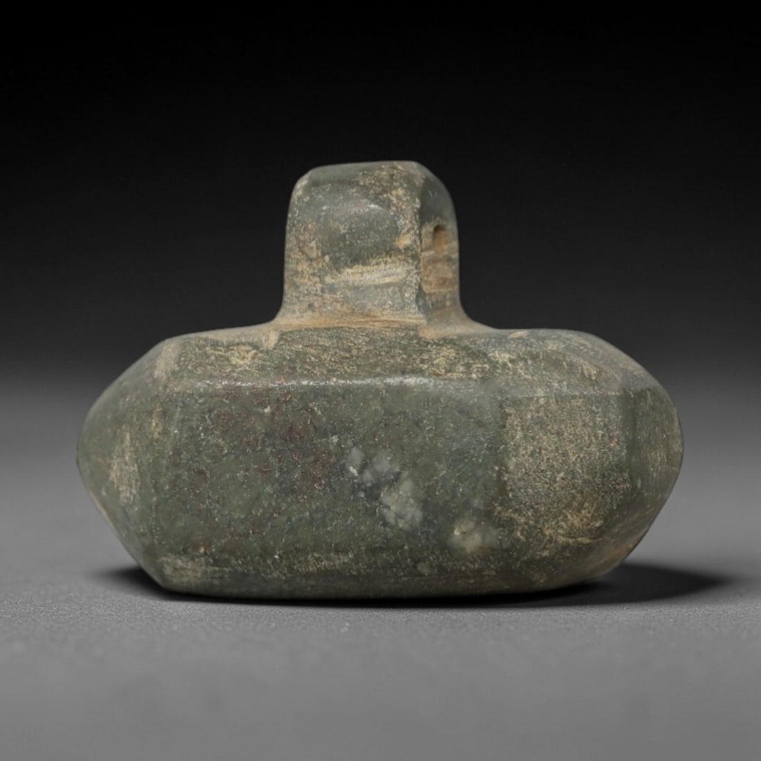 Ancient Stone Mace Head Amulet - Near Eastern Carving, 4AG: This artifact is a carved stone amulet of Near Eastern origin, crafted from a mottled greenish-grey stone with lighter mineral veining and inclusions. Its form features a robust, faceted ovoid body wi