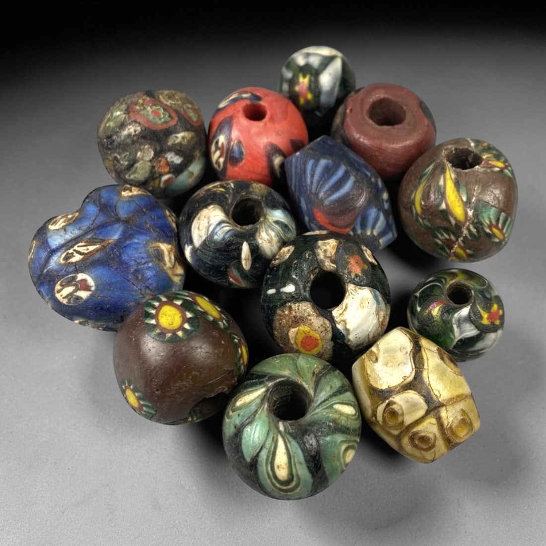 Antique Venetian Glass Beads - 13 Pieces, 13ZT: This set of 13 antique Venetian glass beads features varied hand-formed shapes including spherical, barrel, and irregular forms, crafted from polychrome glass with intricate mosaic and cane-work patte