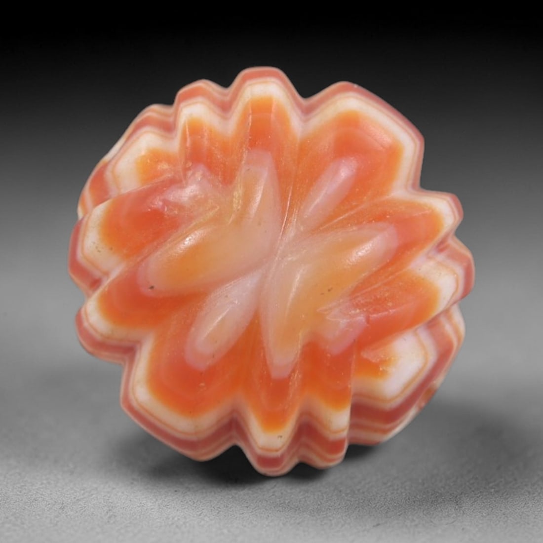 Antique Agate Flower Bead - Central Asian Carved Gemstone, 8AR: Carved from banded agate with vibrant orange and creamy white concentric banding, this bead features a symmetrical multi-petaled floral form with deeply carved, raised petals. A lateral perforation co