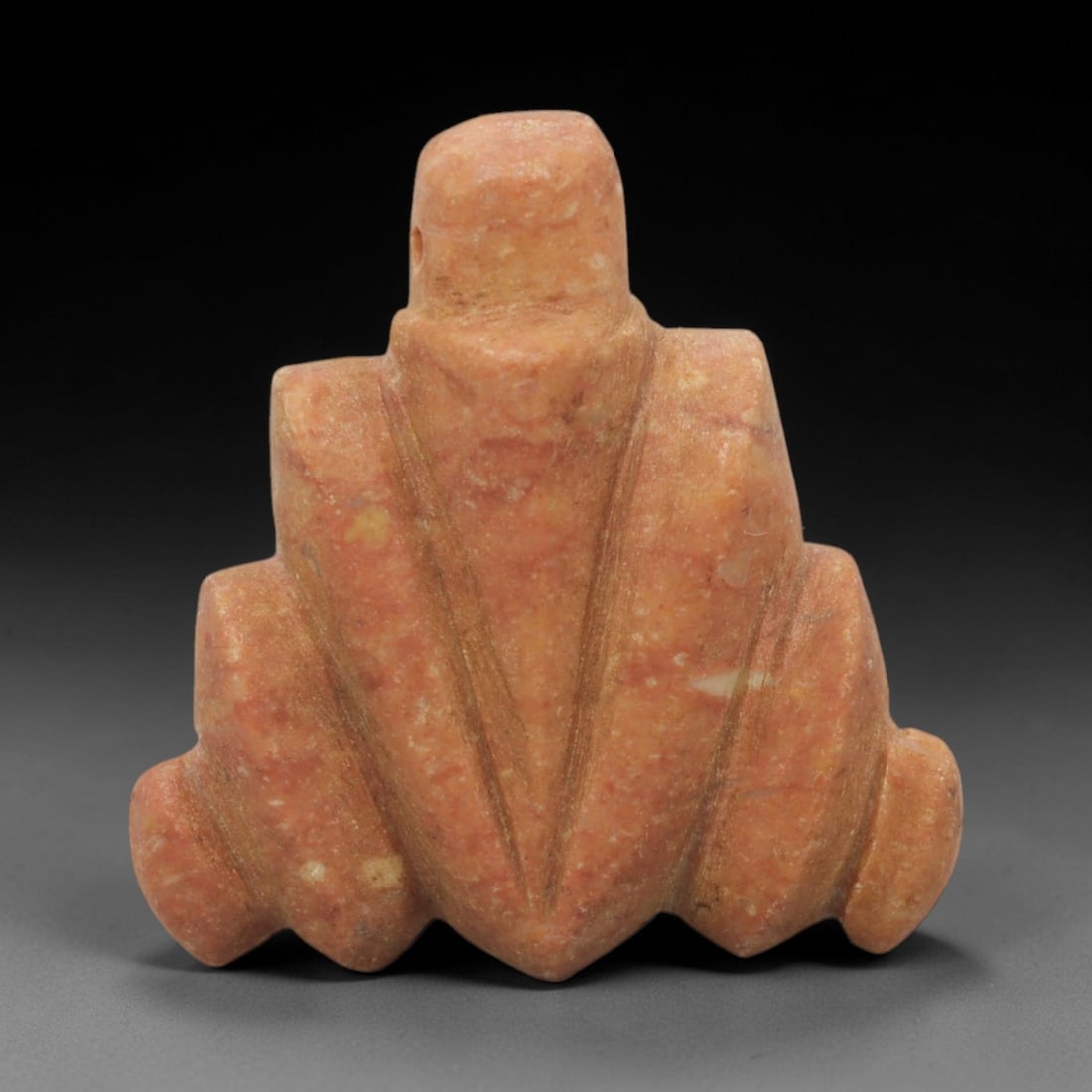 Ancient Stone Tyet Amulet - Egyptian Pendant, 93XQ: Carved from a warm, speckled reddish-orange stone, this amulet takes the form of the Egyptian Tyet (Knot of Isis), featuring a cylindrical top with a perforation for suspension, symmetrical angular si