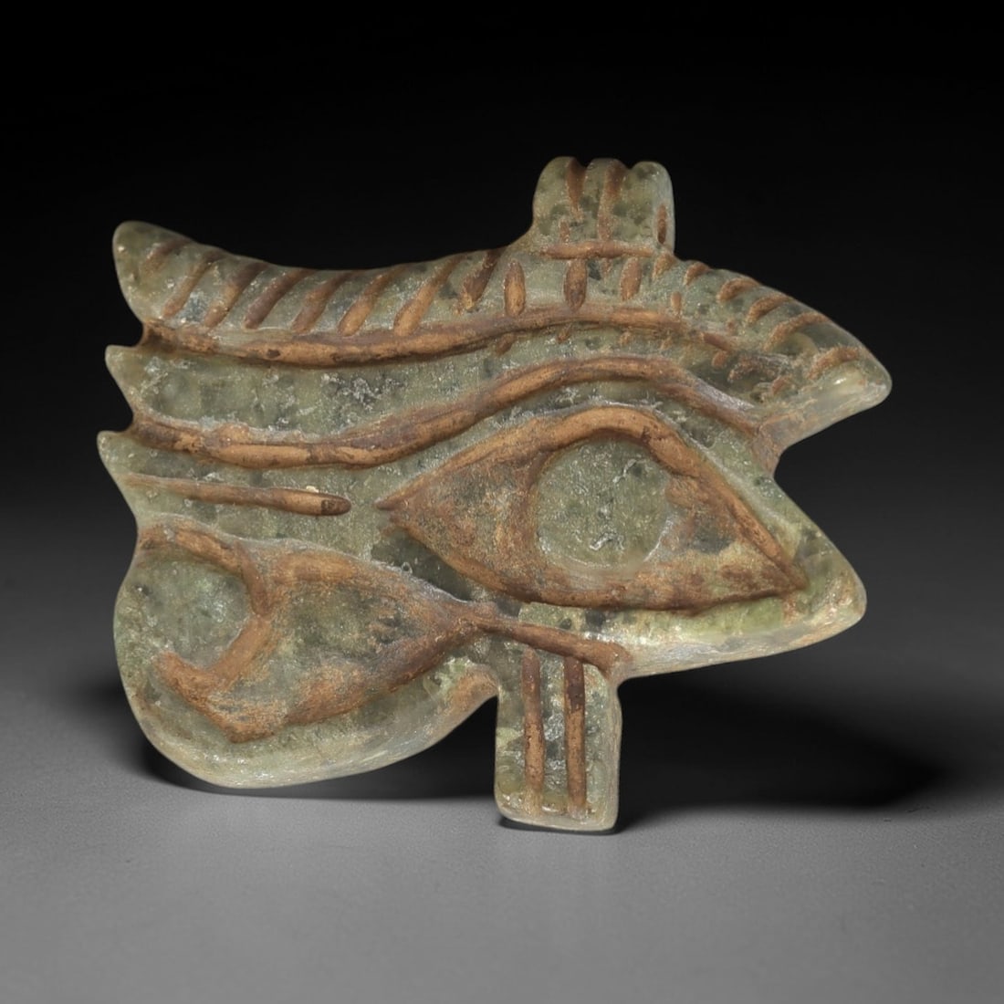 Ancient Serpentine Wedjad Eye - Egyptian Amulet, 46AM: This Wedjad Eye amulet is carved from a mottled serpentine stone, exhibiting a translucent pale green hue with earthy brown inclusions and a matte, aged patina consistent with ancient Egyptian materia