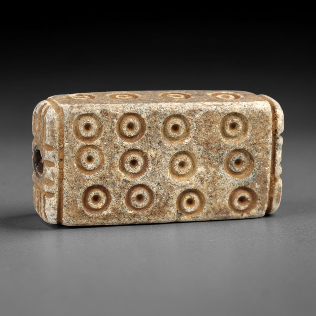 Ancient Steatite Amulet - Near Eastern Concentric Circles, 37AK: Crafted from steatite, this rectangular prism amulet features deeply incised concentric circle motifs arranged in a dense grid across its primary face, with subtle linear carvings along the lateral ed
