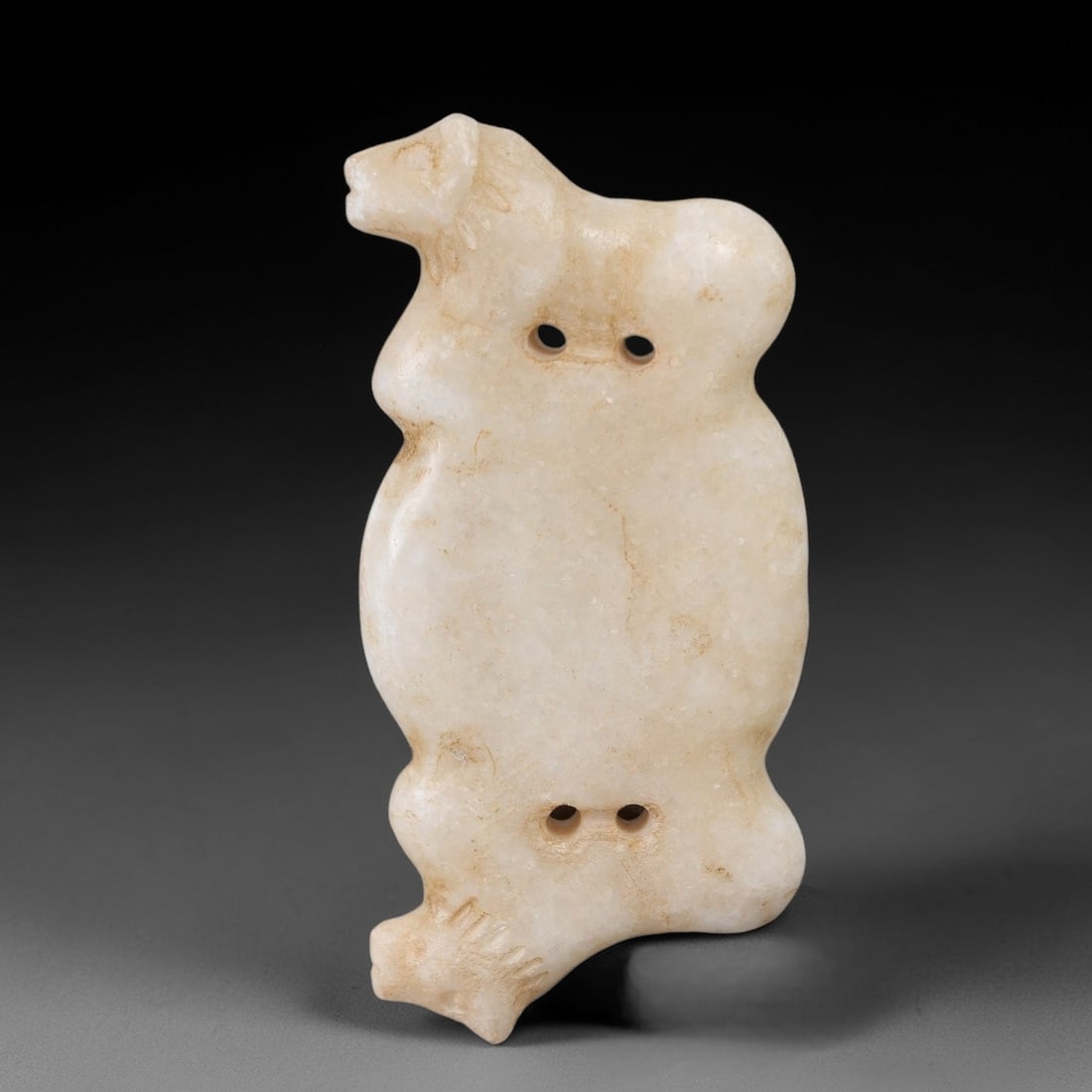 Ancient Marble Double Feline - Near Eastern Amulet Figurine, 19AK: Crafted from pale marble, this amulet features two stylized feline figures positioned at the upper and lower ends of an elongated, lobed body. The upper feline is rendered in profile with incised deta