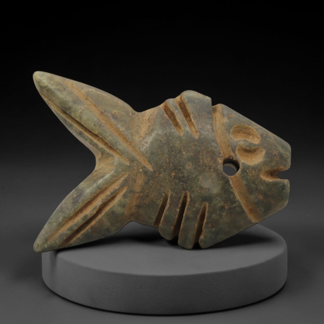 Ancient Stone Fish - Egyptian Amulet Pendant, 99XQ: Carved from mottled green stone, this amulet depicts a stylized fish with incised linear details defining its fins, tail, and facial features, including a drilled suspension hole for threading as a we