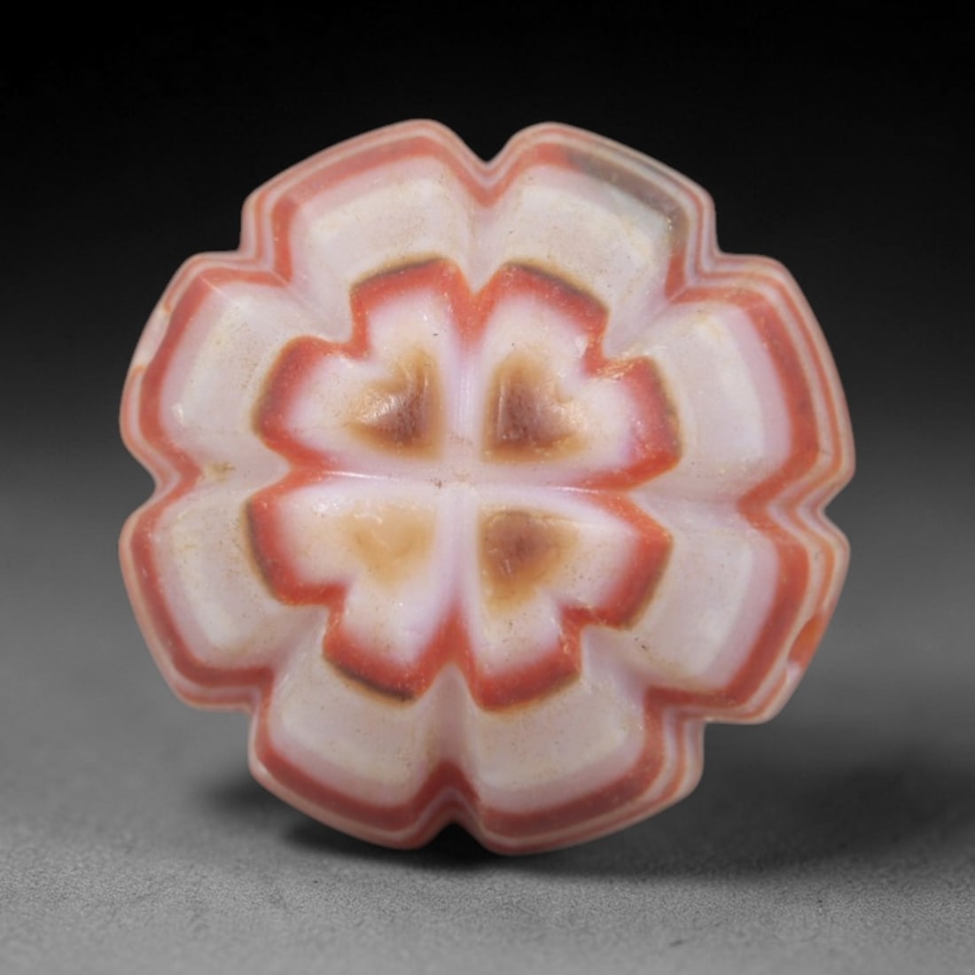 Antique Agate Star Bead - Central Asian Carved Gemstone, 5AR: Carved from banded agate with warm orange and creamy white concentric banding, this bead features a symmetrical multi-pointed star form with scalloped, layered edges. A lateral perforation confirms it