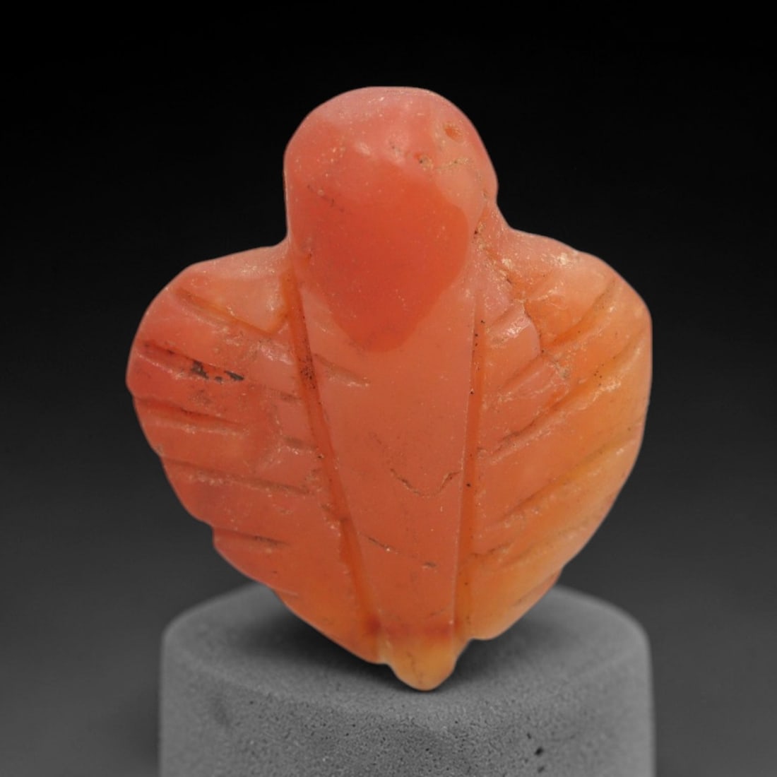 Ancient Carnelian Fly - Egyptian Amulet Figurine, 67XS: Carved from warm, opaque carnelian with natural surface patination and minor wear, this amulet depicts a stylized fly, characterized by a rounded head, broad wing-like body, and incised linear details