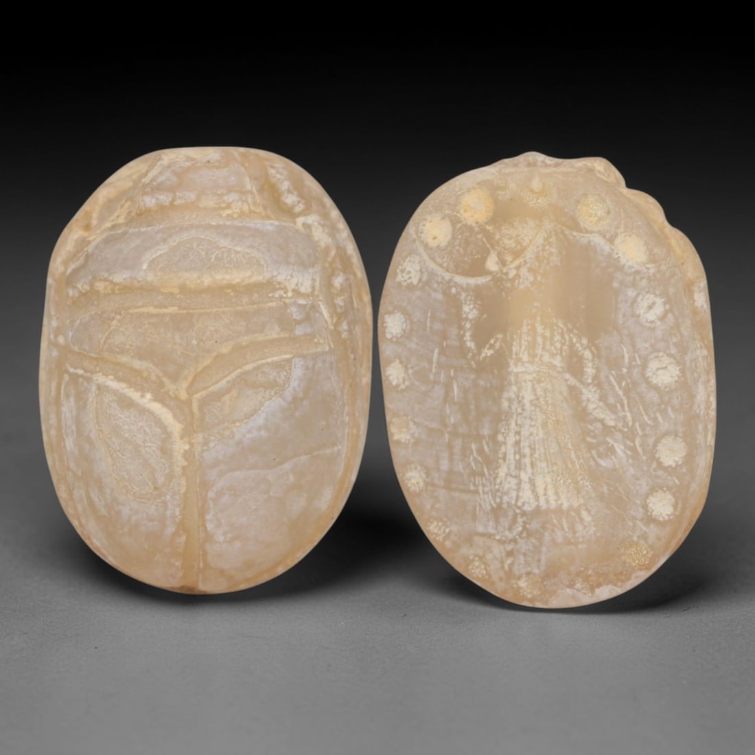 An Ancient Near Eastern Chalcedony Scarab Stamp Seal, 1st Millennium BCE, 97AC: Carved from translucent chalcedony with a pale, milky patina and subtle internal veining, the object is formed as an oval scarab seal. The dorsal side is modeled in low relief with a segmented carapac