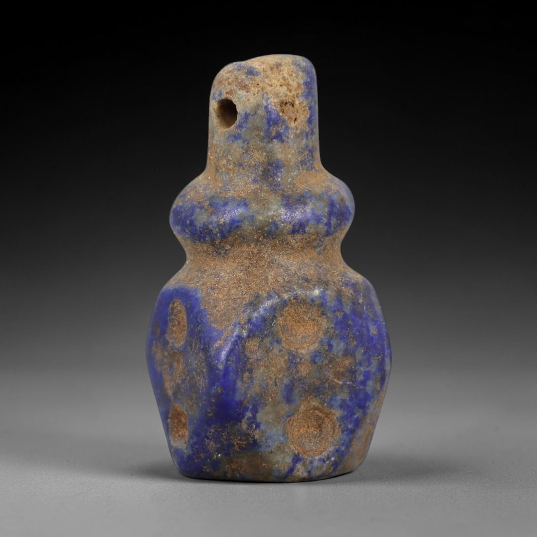 Ancient Lapis Lazuli Amulet - Egyptian Ritual Pendant, 27AP: Carved from lapis lazuli, this amulet features a stepped, bulbous form with a drilled suspension hole piercing the upper lug, its surface marked by recessed circular indentations. The deep blue stone