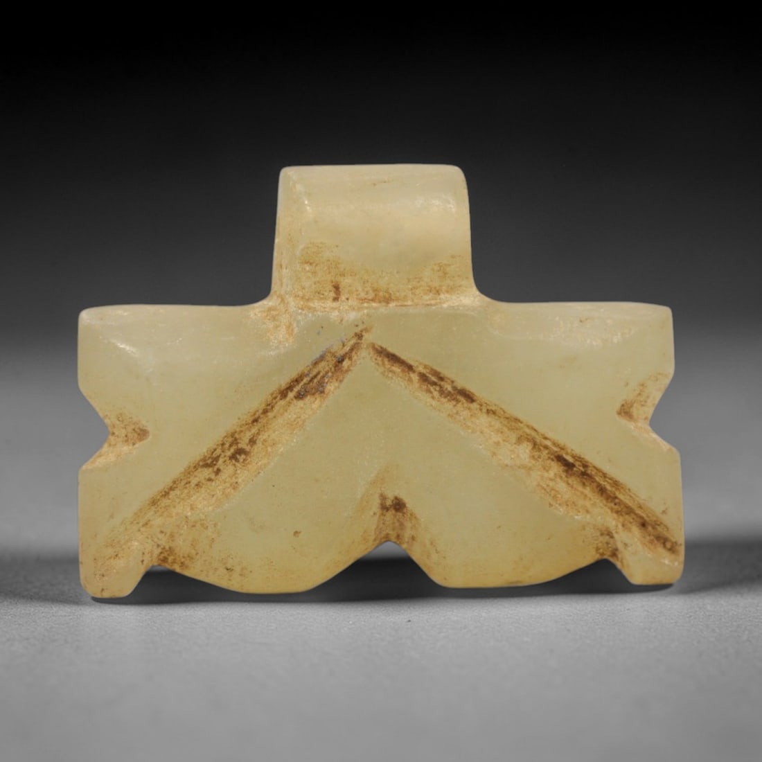 Ancient Serpentine Amulet - Near Eastern Chevron Pendant, 72ZW: This amulet is carved from pale yellow serpentine, featuring a geometric chevron form with a rectangular suspension loop at the top. Incised diagonal lines define the central V-shaped motif, with eart