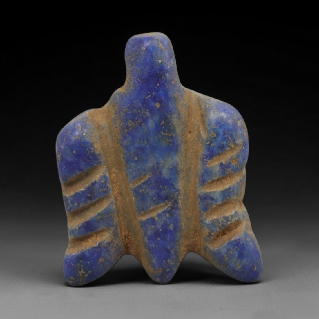 Ancient Lapis Lazuli Fly Amulet - Egyptian Ritual Pendant, 38ZT: Carved from lapis lazuli, this amulet is formed in the shape of a fly, with a broad, trapezoidal body and a raised upper lug pierced for suspension, its surface incised with linear details defining th
