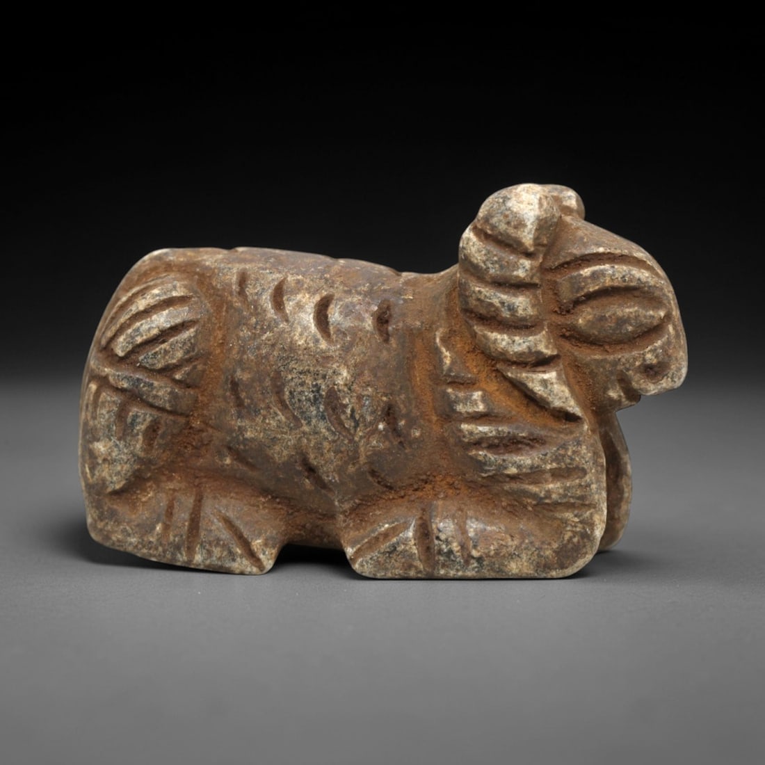 Ancient Schist Ram - Zoomorphic Amulet Figurine, 66ZP: This zoomorphic amulet is carved from schist, shaped into a recumbent ram with incised linear details defining the curled horns, textured fleece, and stylized limbs. Stylistically consistent with Near