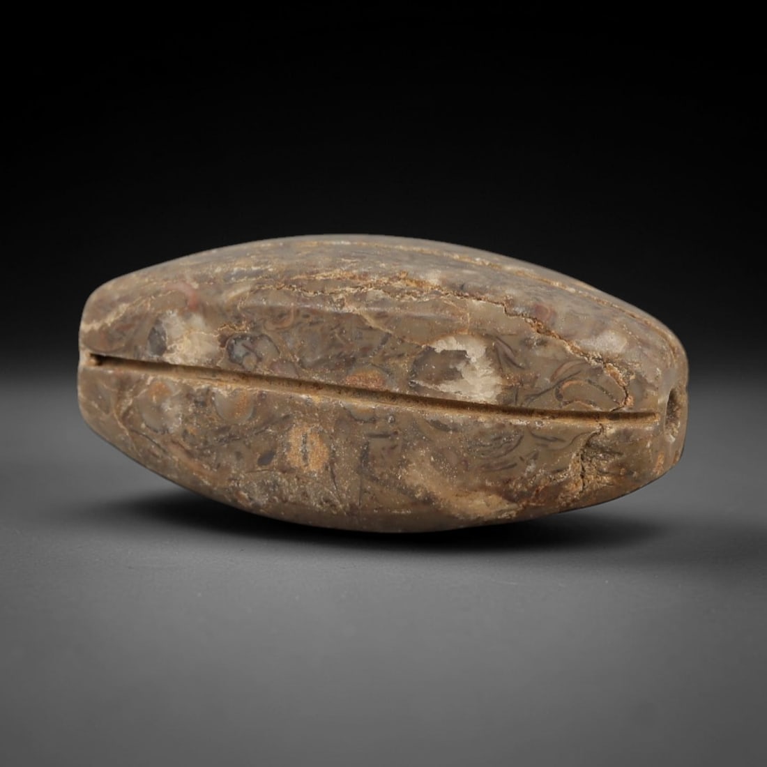 Ancient Egyptian Stone Amulet - Barrel-Shaped Carving, 33AG: Carved from stone, this ancient Egyptian barrel-shaped amulet features a rounded central form with incised linear detailing, typical of protective amulets from the Late Period (c. 664-332 BCE). The si