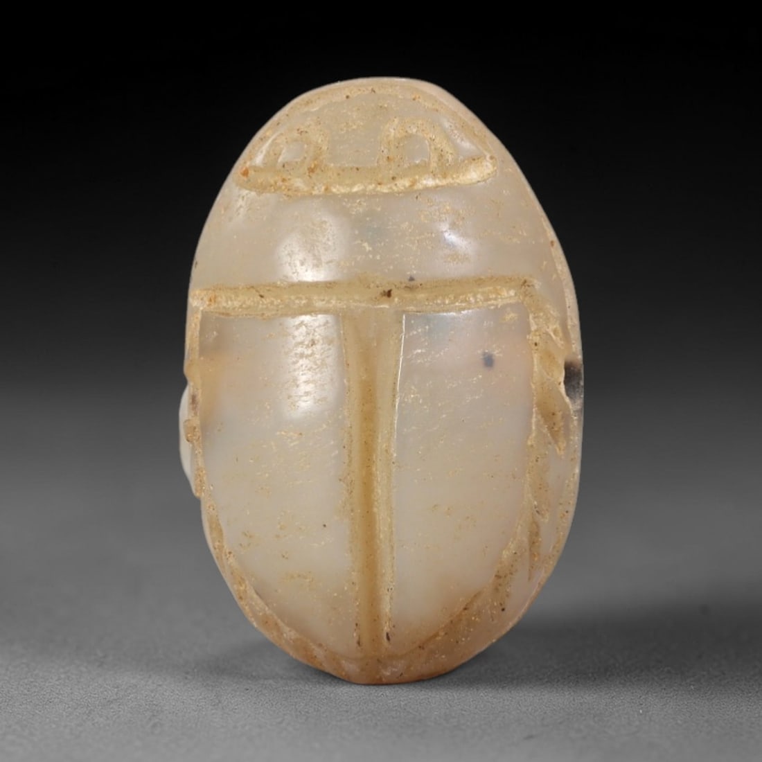 Ancient Chalcedony Scarab Amulet - Egyptian Figurine, 25AR: This artifact is carved from pale, milky-white chalcedony, exhibiting a smooth, polished surface with subtle natural inclusions and faint surface wear consistent with age. The form is a classic scarab