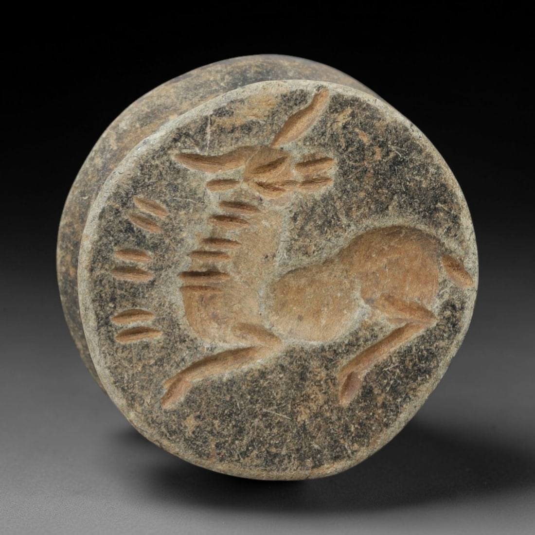 Ancient Stone Amulet - Near Eastern Stamp Seal Figurine, 61AH: Carved from stone, this ancient Near Eastern double convex stamp seal amulet features a stylized animal motif typical of early glyptic art in the region. The piece exhibits precise linear detailing an