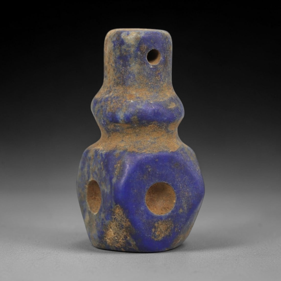 Ancient Lapis Lazuli Ritual Pendant - Egyptian Amulet, 35ZT: Carved from lapis lazuli, this amulet features a stylized bottle-shaped form with a cylindrical upper lug pierced for suspension, and additional circular holes on the lower hexagonal body. The deep bl