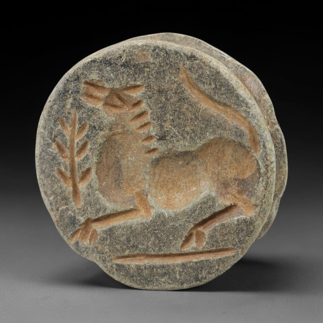 Ancient Stone Amulet - Near Eastern Stamp Seal Figurine, 34AH: Carved from stone, this ancient Near Eastern double convex stamp seal amulet features a stylized animal motif typical of early glyptic art in the region. The piece exhibits precise linear detailing an
