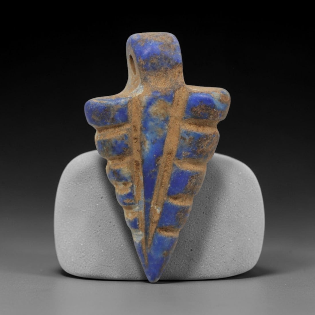 Ancient Lapis Lazuli Arrowhead Amulet - Egyptian Ritual Pendant, 20ZT: Carved from lapis lazuli, this amulet features a pointed arrowhead form with a raised upper loop pierced for suspension, its body incised with vertical linear details that define protective motifs. Th