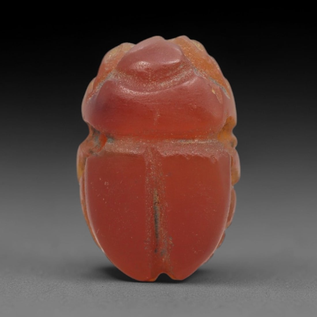 Ancient Carnelian Scarab Amulet - Egyptian Figurine, 80XS: Carved from warm, translucent orange-red carnelian with natural tonal gradients and subtle surface patination, this amulet is formed as a stylized scarab beetle with incised linear detailing to define