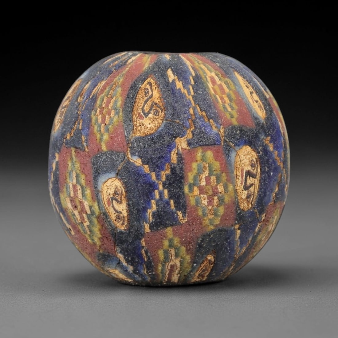 Ancient Glass Face Bead - Egyptian Amulet Bead, 32ZM: This ancient bead is crafted from polychrome glass, formed using core-formed and trailed decorative techniques characteristic of Egyptian glassworking traditions. The spherical form features multiple