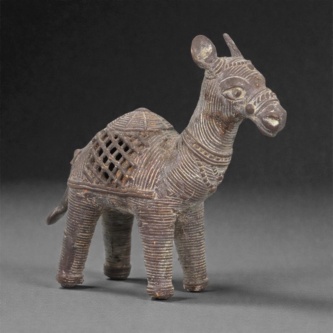 An African Bronze Zoomorphic Figure, 19th-Early 20th Century, 12LN: Cast in bronze using the lost-wax technique, the figure depicts a standing animal with short legs, a rounded body, and an elongated head with alert ears and incised facial detailing. The surface is co