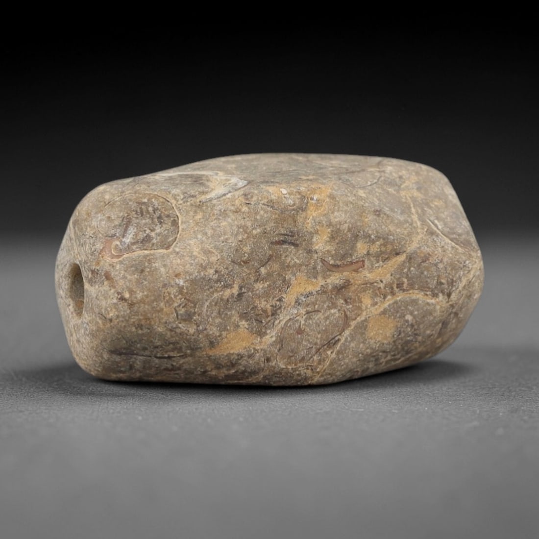 Ancient Egyptian Stone Bead - Natural Vein Carving, 60AE: Carved from stone, this ancient Egyptian bead features natural veining and subtle linear carvings, typical of Late Period beadwork. The compact form has a central perforation, indicating its use as a